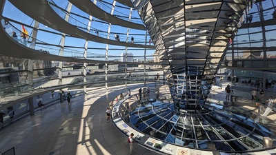The dome of the Bundestag is visible which redirects light along a mirror structure inside the building
